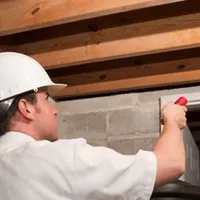 Termite inspection technician checking a basement wall and framing for termite activity in Mesa, AZ